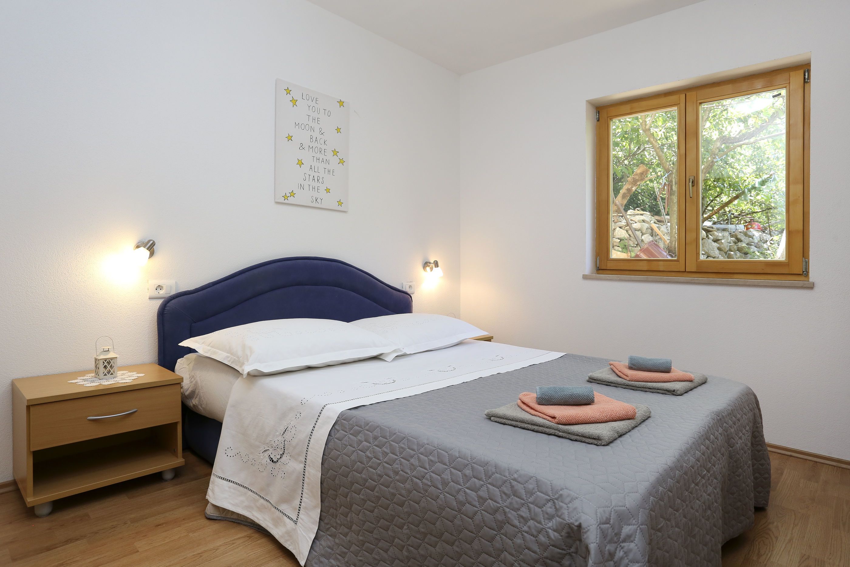 Una camera da letto con un letto, comodini, una finestra e una decorazione a parete.