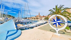 A marina with boats docked, a compass sign, and a historic building in the background. - Apartment Ante (Milna)
