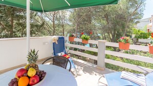 A balcony with a table holding a fruit bowl, a chair, and a blue lounge chair. - Apartment Ante (Milna)