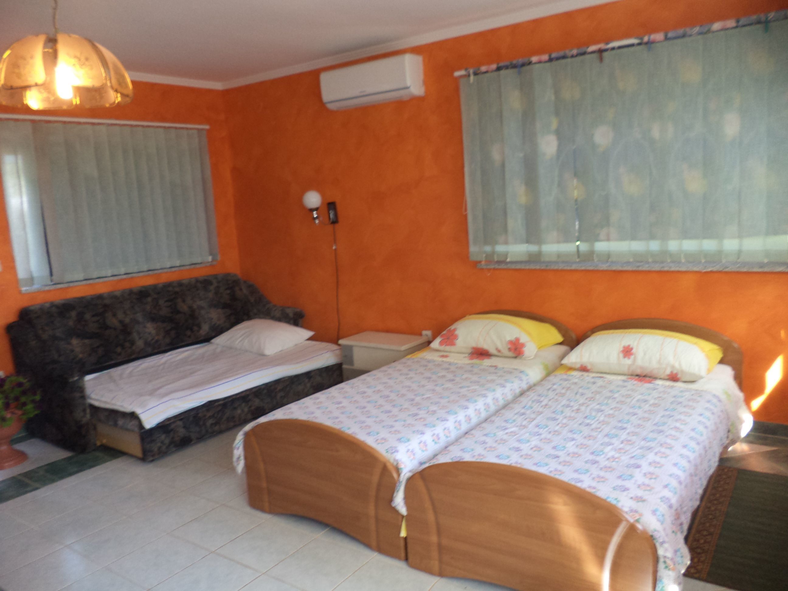 Un dormitorio con dos camas, una mesita de noche, una lámpara y una ventana con cortinas.