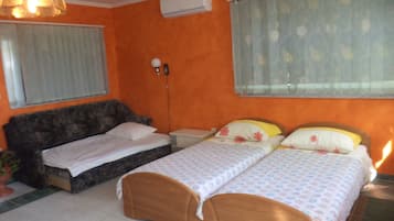 Un dormitorio con dos camas, una mesita de noche, una lámpara y una ventana con cortinas.