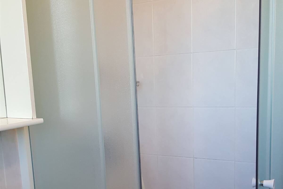 A bathroom with a glass-enclosed shower, a white sink, and a toilet.