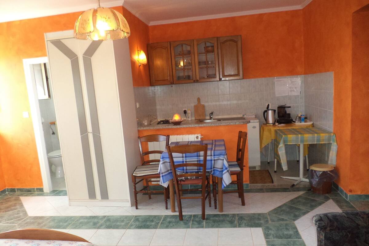A kitchen with wooden cabinets, a dining table with chairs, a small island with a sink, and a refrigerator.