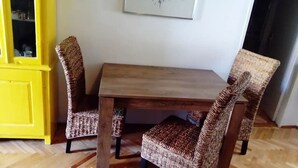 Un coin repas avec une table en bois et des chaises en osier.