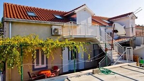 Un immeuble résidentiel doté d’un toit recouvert de tuiles, d’un balcon et d’un escalier menant à un étage supérieur.