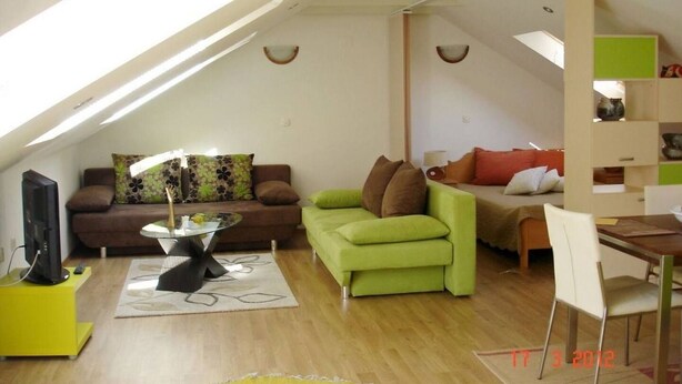 Un espace de vie de style loft avec un plafond en pente, un ensemble de canapés, une table à manger et des étagères intégrées.