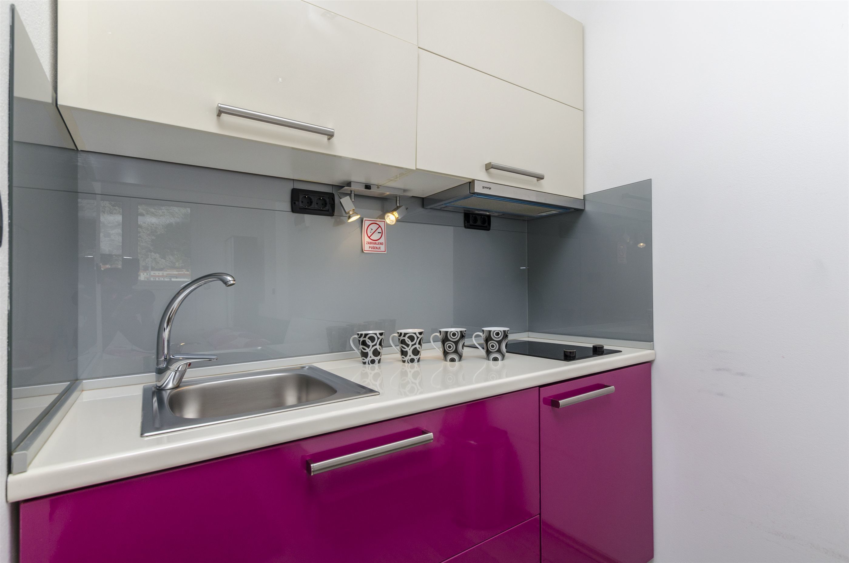 A kitchen with a stainless steel sink, a white countertop, and a 'No Smoking' sign.