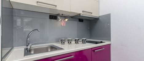 A kitchen with a stainless steel sink, a white countertop, and a 'No Smoking' sign.