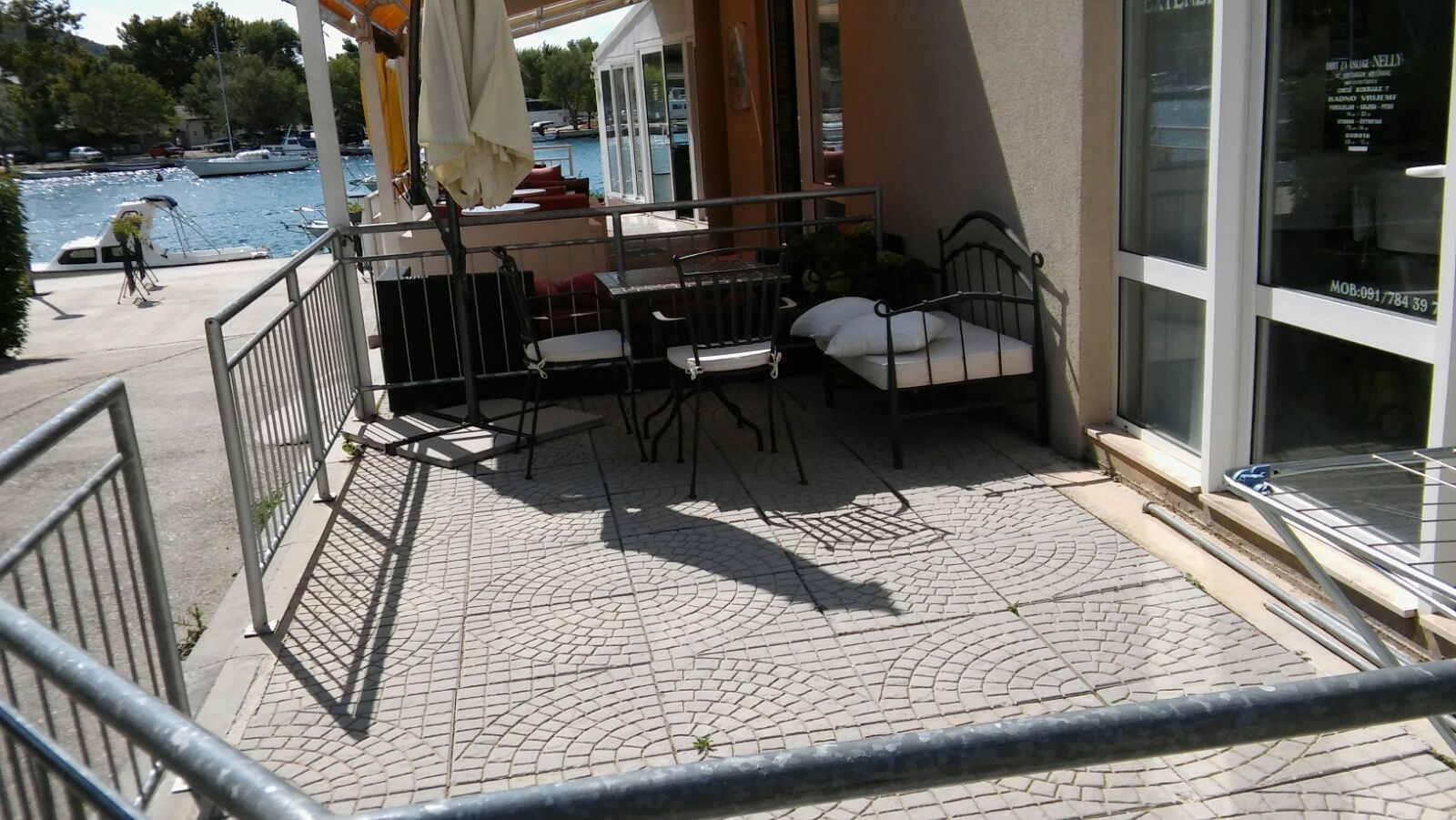 Un balcon avec une balustrade en métal, un lit et une table avec des chaises.