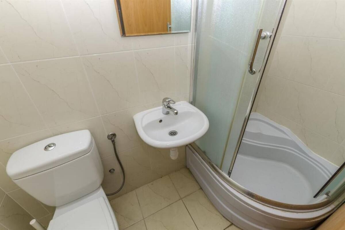 Un bagno compatto con il water, lavandino e doccia vetro-murata.