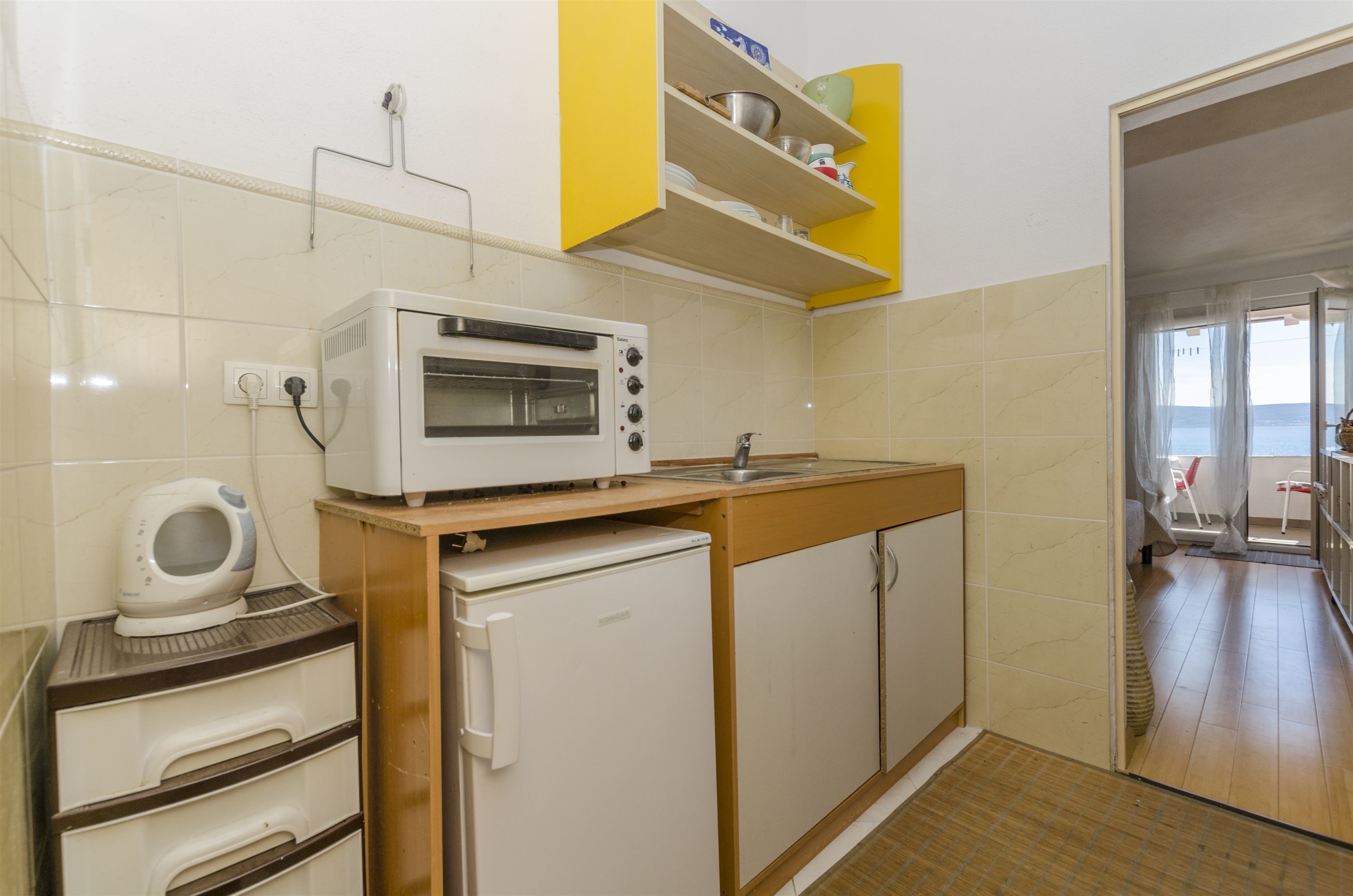 A compact kitchen with a built-in oven, a small refrigerator, and a microwave on the countertop.
