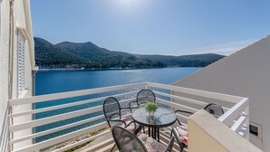 Ein Balkon mit Tisch und Stühlen mit Blick auf einen See, im Hintergrund Berge.