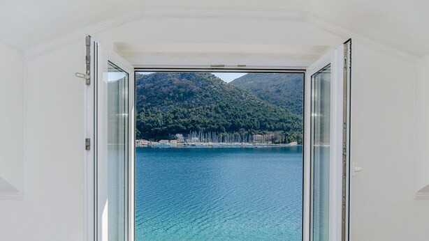 Ein Zimmer mit einer großen Glasdoor, die zu einem malerischen Blick auf einen See und Berge führt.