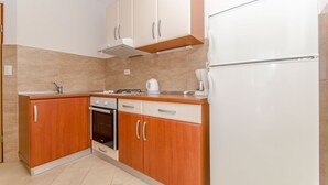 Eine Küche mit Holzschränken, einem weißen Kühlschrank, einem Herd und einem Spülbecken.