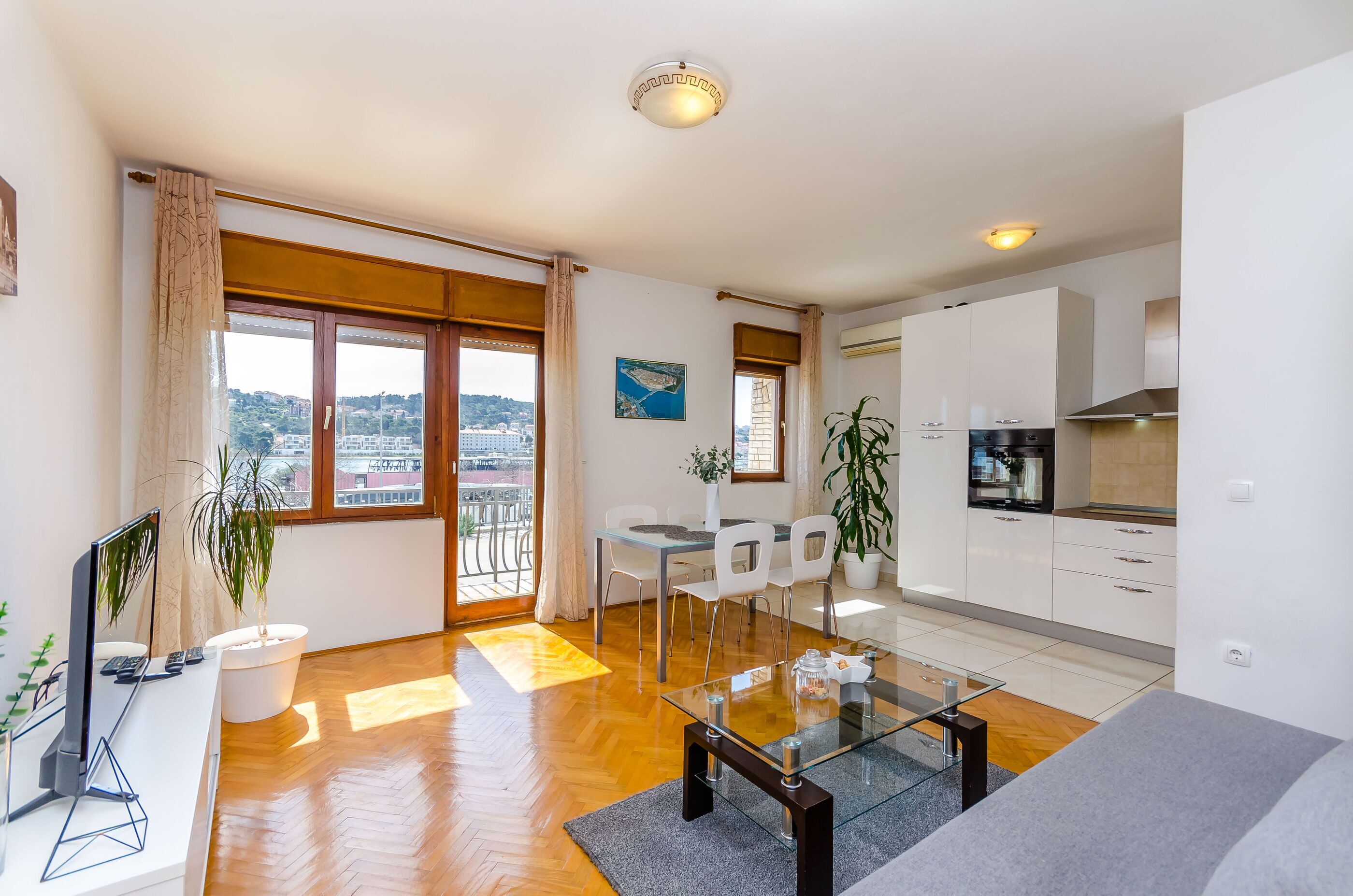 A modern apartment with a dining area, kitchen, and large windows with a city view.