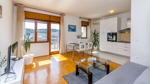 Un appartement moderne comprenant un coin repas, une cuisine et de grandes fenêtres offrant une vue sur la ville.