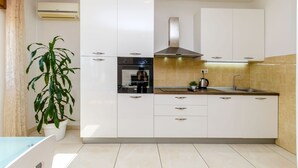 Une cuisine moderne avec des meubles blancs, une hotte en acier inoxydable et un évier.