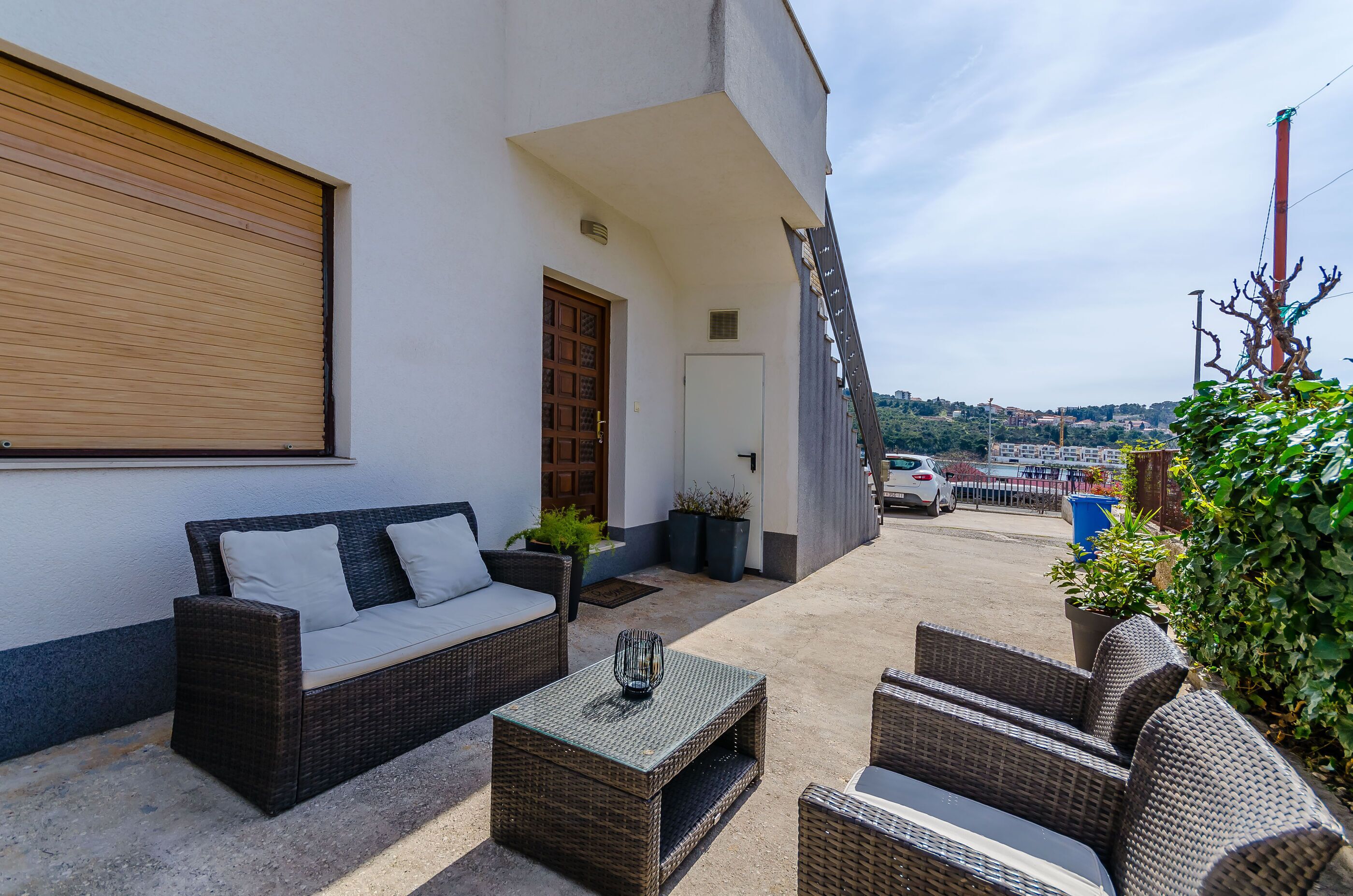 An outdoor seating area with wicker furniture, a door, and a view of the city in the background.