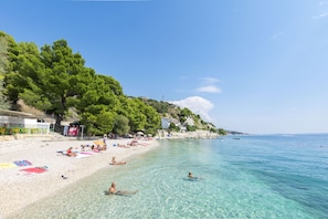 A beach with clear water, people sunbathing, and a few boats. - Apartment Temza (Krilo Jesenice)