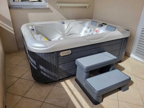Een hottub met een opstapje voor gemakkelijke toegang, een bedieningspaneel en een label met het merk 'Wells'.