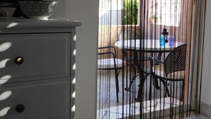 A room with a white cabinet, a patterned bowl on top, and a view of an outdoor patio with a table and chairs. - Apartments Mirjana (Milna)