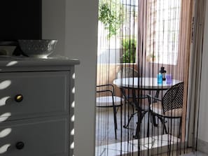 Une pièce avec un meuble blanc, un bol décoré posé sur le dessus, et une vue sur une terrasse extérieure avec une table et des chaises.