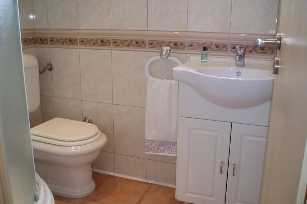 Un baño con inodoro, lavamanos y mueble de almacenamiento.