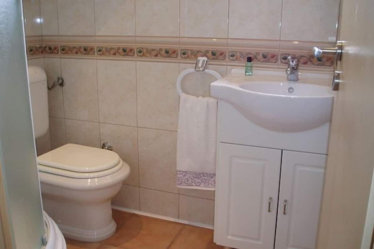 Un baño con inodoro, lavamanos y mueble de almacenamiento.