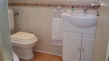 A bathroom with a toilet, sink, and cabinet.