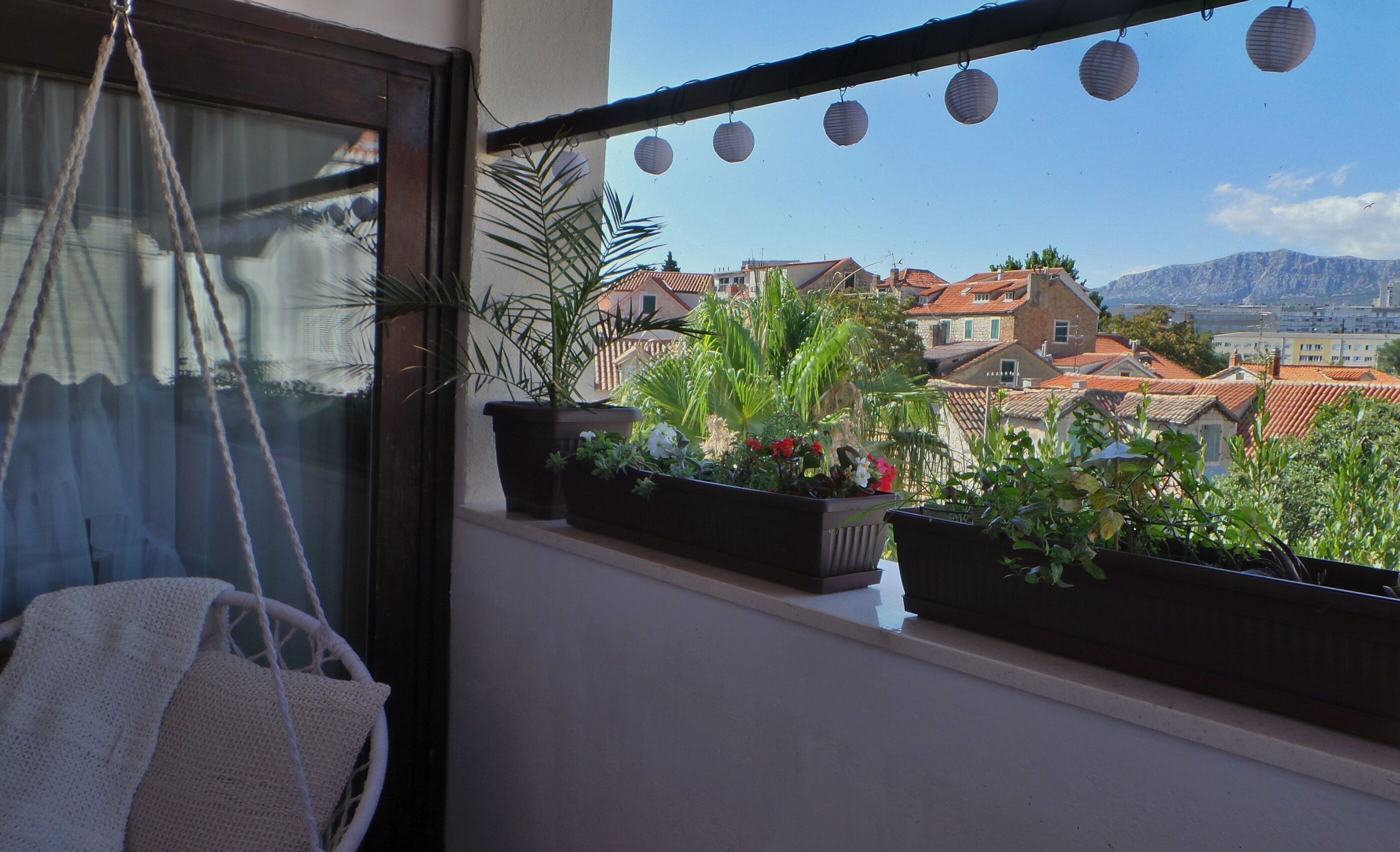 Un balcon agrémenté de plantes en pot et de lanternes en papier suspendues.