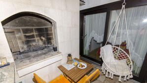 A stone fireplace, a hanging chair, and a table with a plate of food and a drink. - Apartment Taida (Split)