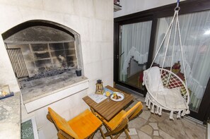 A stone fireplace, a hanging chair, and a table with a plate of food and a drink.