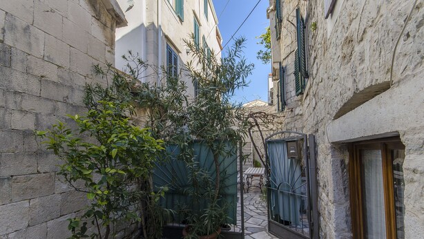 A narrow alleyway with stone walls, a potted plant, and a gate. - Apartment Taida (Split)