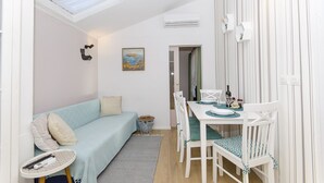 A compact living space with a sofa, a dining table with chairs, a small side table, and a ceiling light. - Apartment Taida (Split)
