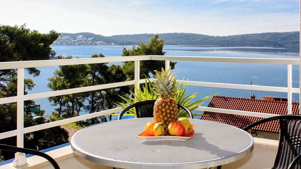 A balcony with a round table, a pineapple, and a plate of fruit. - Apartment Marin (Trogir)