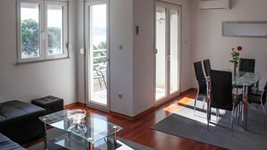 A modern living room with a glass coffee table, a sofa, and a dining area with chairs and a table. - Apartment Marin (Trogir)