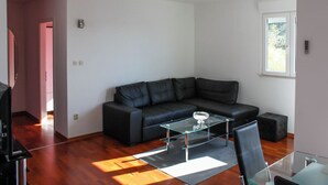 A modern living room with a black leather sofa, a glass coffee table, and a black leather chair. - Apartment Marin (Trogir)