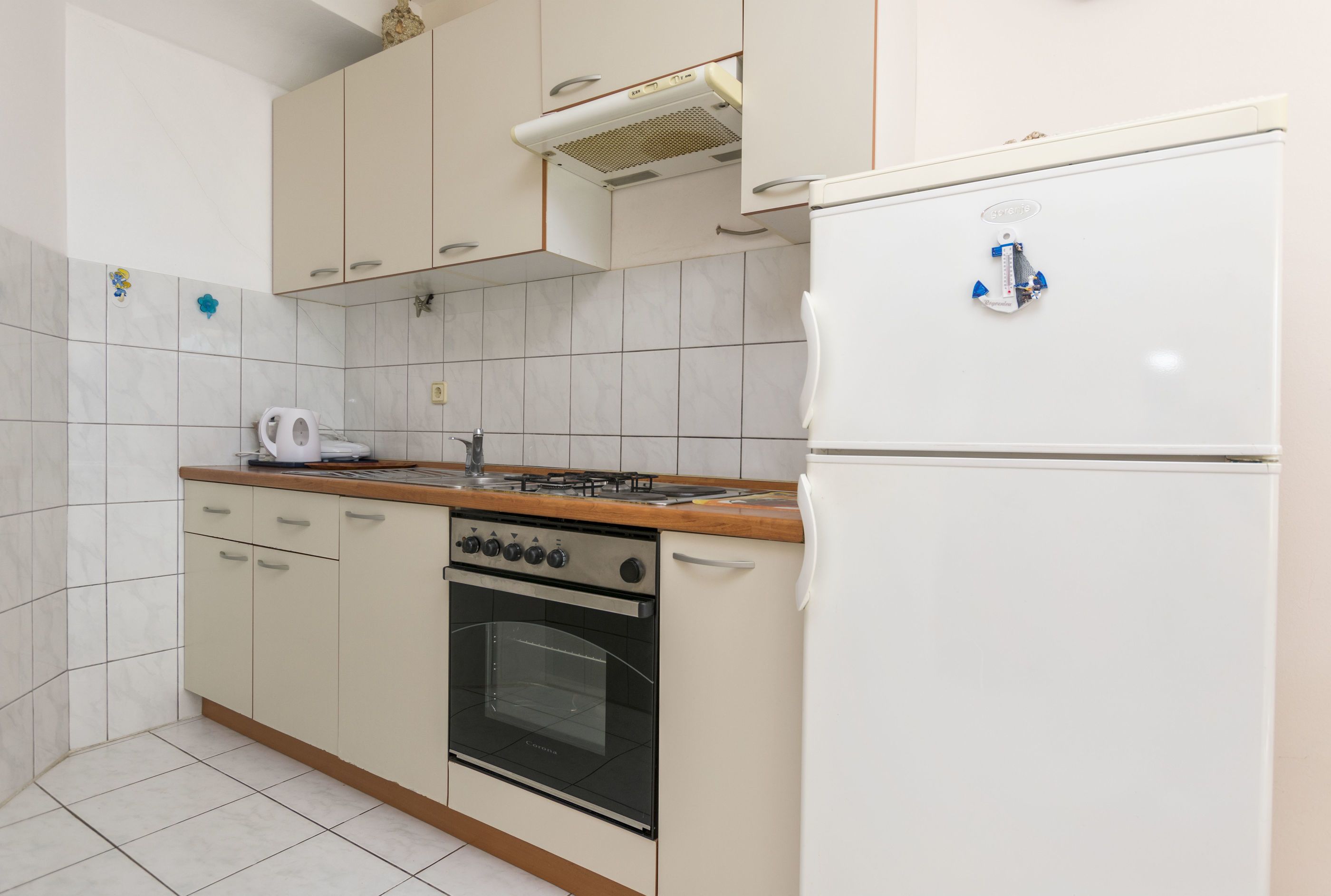 A compact kitchen with a gas stove, oven, and a white refrigerator.