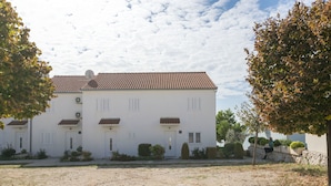 A white building with a tiled roof, multiple doors, and small windows. - Apartments Gloria (Rogoznica)