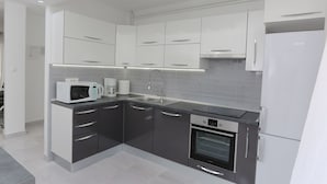 A modern kitchen with white cabinets, a built-in oven, and a microwave. - Apartment Lucija (Supetar)