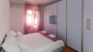 A bedroom with a bed, a dresser, a mirror, and a window with curtains. - Apartment Lucija (Supetar)