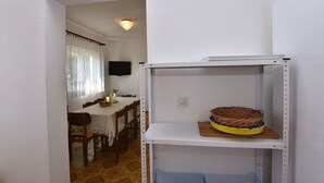 Un comedor con una mesa y sillas, un televisor en la pared y un estante con una cesta.
