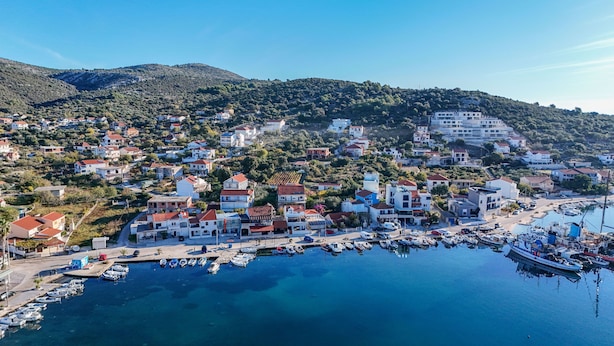 Une ville côtière dotée d’un port de plaisance, de maisons et bordée de collines.