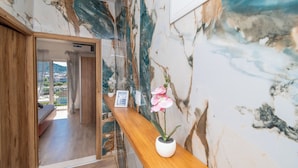 A hotel reception area with a marble wall, a wooden reception desk, and a potted orchid. - Apartments Barbara (Poljica)