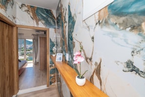 A hotel reception area with a marble wall, a wooden reception desk, and a potted orchid.