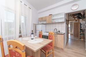 Eine moderne Küche mit Holzausstattung, einem weißen Kühlschrank und einer Essecke mit Tisch für zwei Personen.
