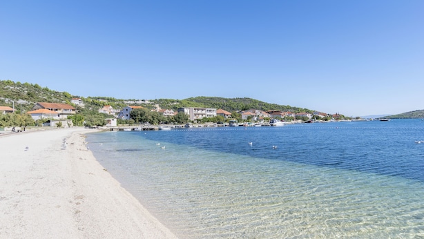 A coastal town with clear waters, sandy beach, and buildings along the shore. - Apartments Barbara (Poljica)