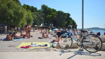En strand med mennesker, der solbader, en cykel og parasoller.