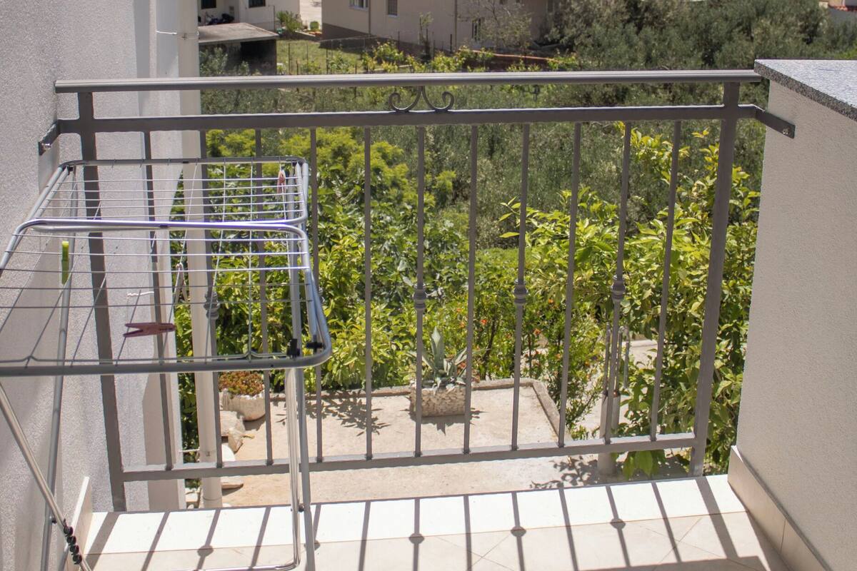 Een balkon met een metalen hekwerk dat uitkijkt over een woongebied met gebouwen en een waterpartij in de verte.