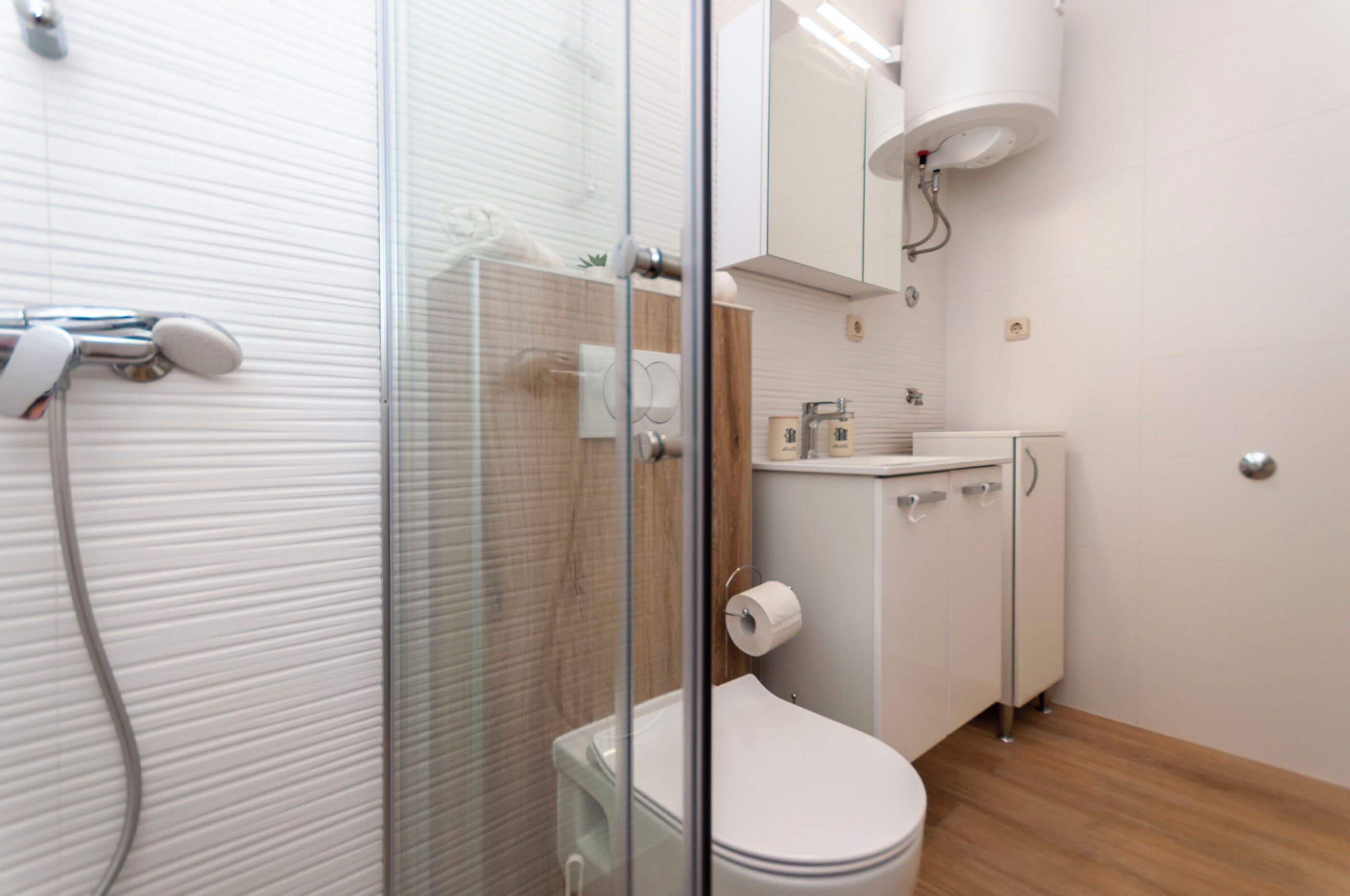 Une salle de bain moderne avec une douche à parois de verre, des toilettes, un lavabo et un meuble de rangement.